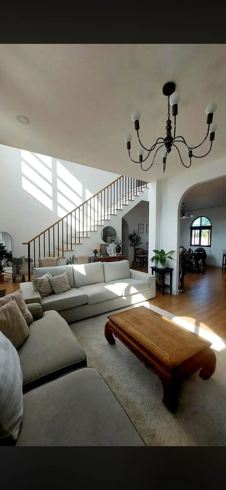 Furnished living room with stairs and a view through to the dining room.