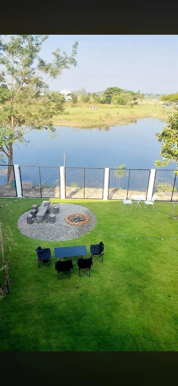 Garden with outdoor seating and water beyond the fence.